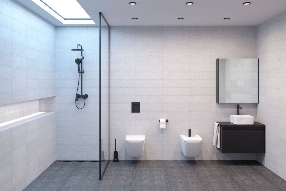 A white bathroom interior with a glass shower wall with white fixtures and lavatory