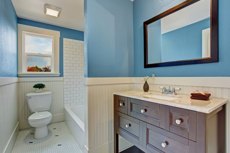 Bathroom interior with blue wall and white plank panel trim. Bath tub with tile wall trim - Gap Between Vanity Top And Wall? Here's What To Do