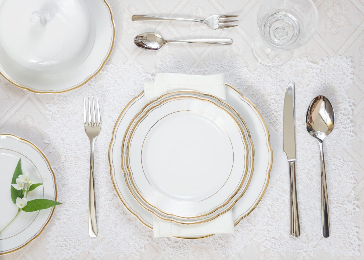 Beautifully decorated table with white plates, crystal glasses, linen napkin and cutlery are on luxurious tablecloth