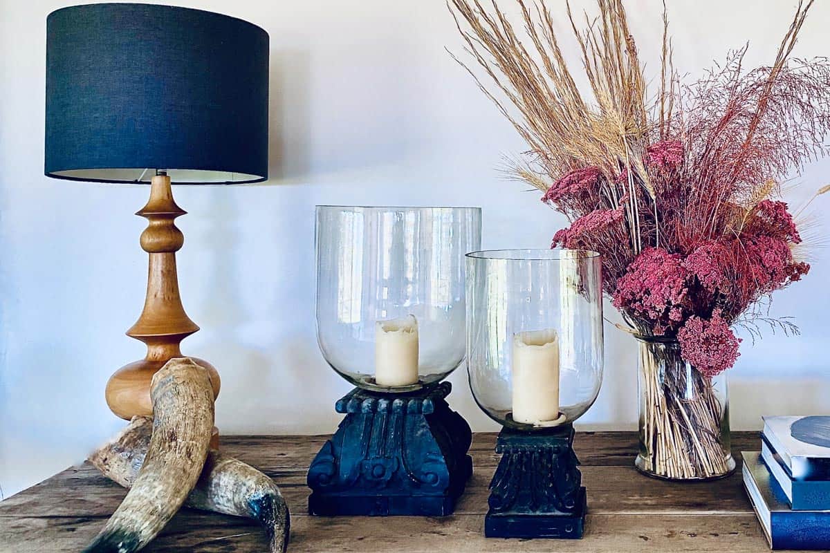 A candle holders in a wooden table with dried flowers in the vase, animal horns and lampshade, What Can You Put In A Candle Holder Besides Candles?