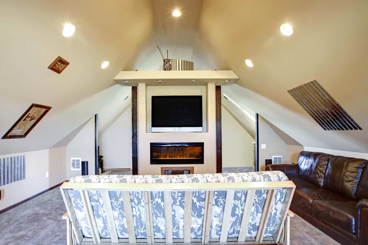 A chic attic living room with sloped ceiling, What Are The Best Lighting Options For A Sloped Ceiling?