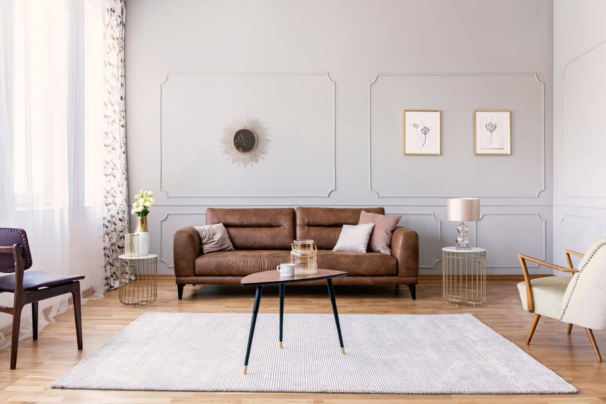 Coffee table with vase and mug in the middle of elegant living room interior with comfortable leather sofa