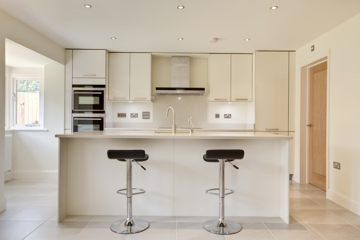 Contemporary modern cream colored luxury kitchen with fitted appliances and breakfast bar
