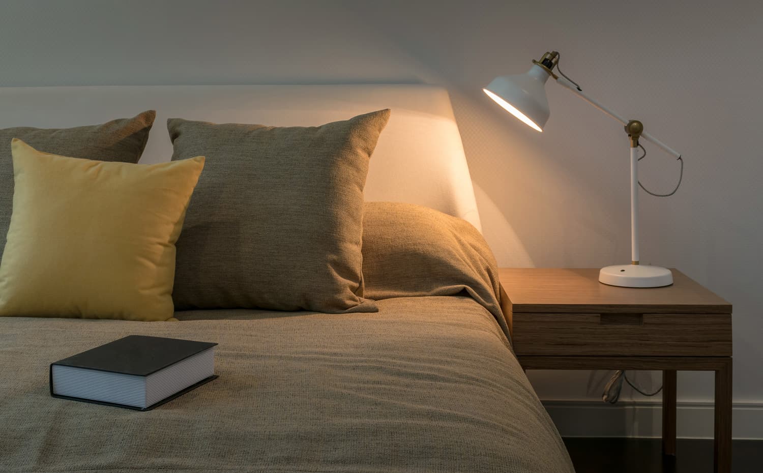 Cozy bedroom interior with book and reading lamp on bedside table