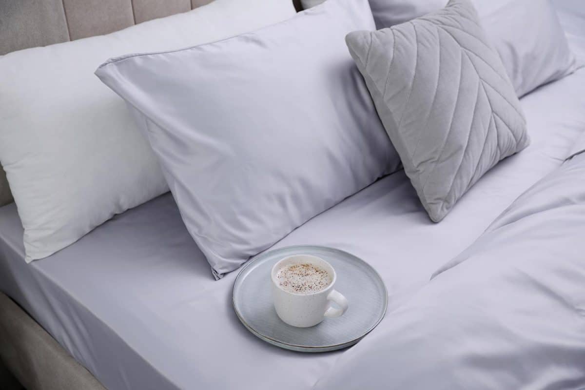 Cup of coffee on bed with soft silky bedclothes