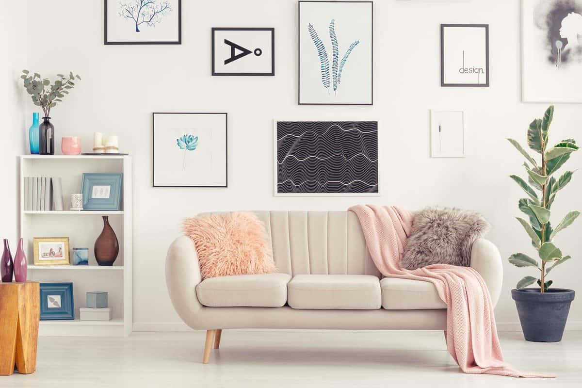 Elegant sofa, white shelf with decorations and posters on the wall in a living room