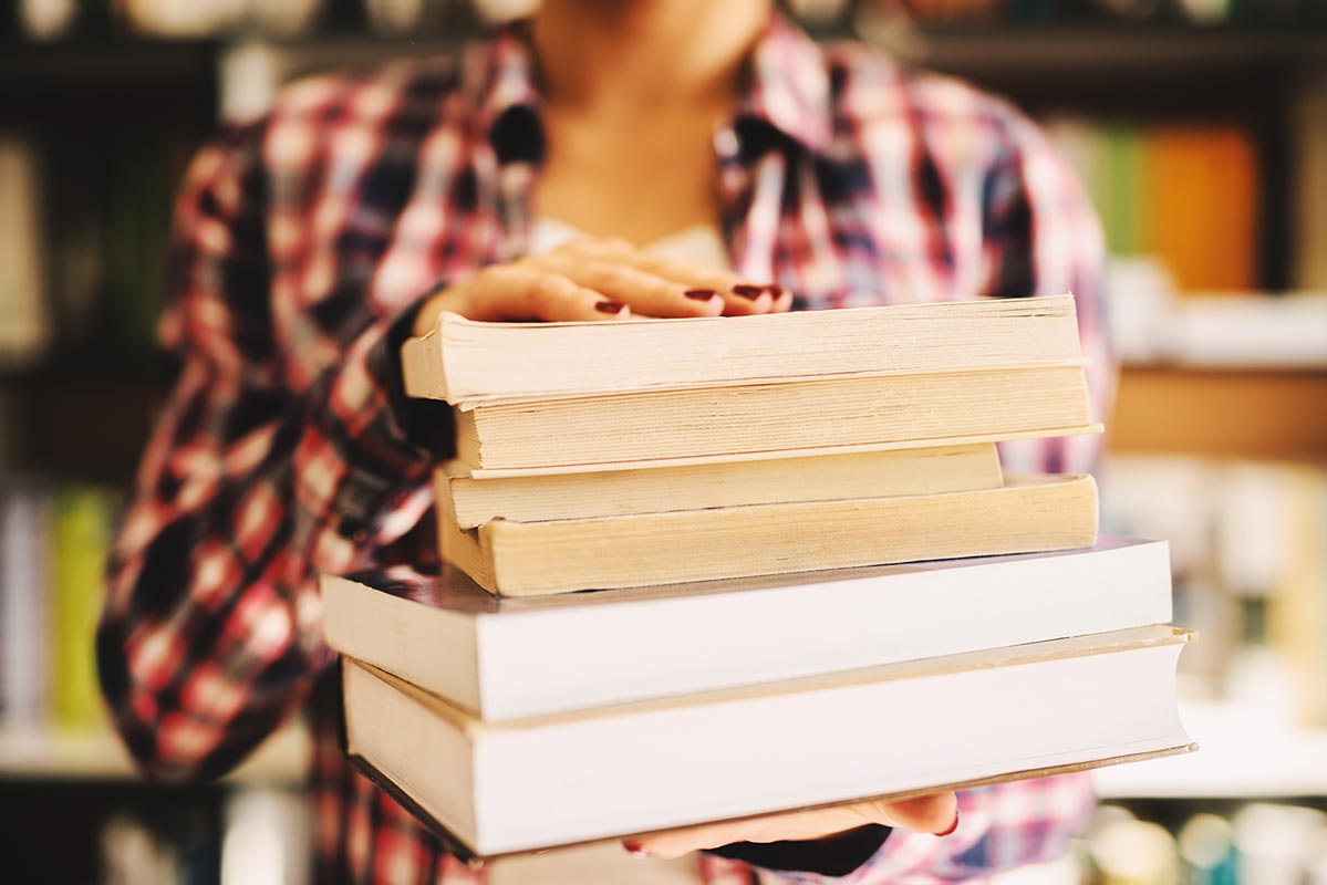 Females hands holding books in front of the camera