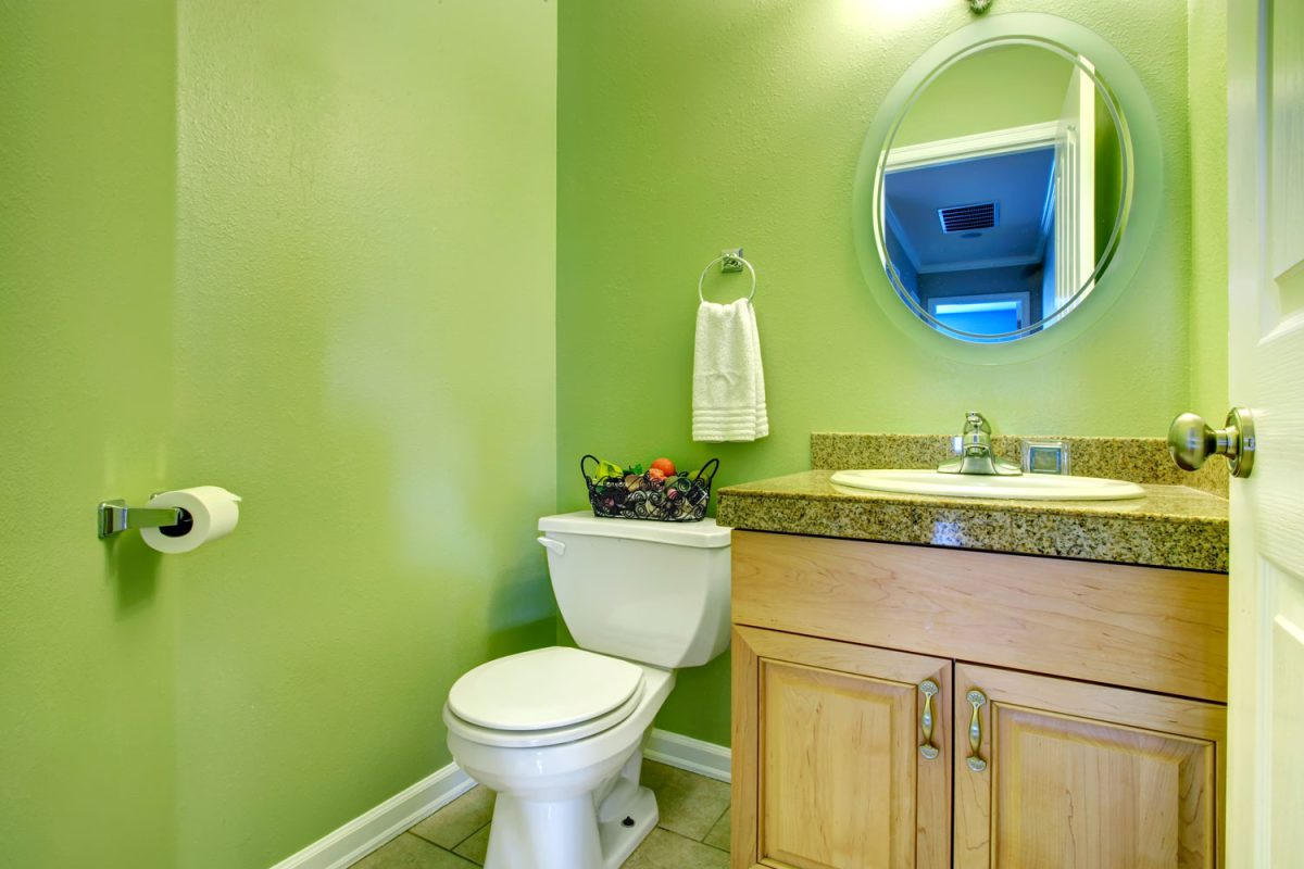 Green painted bathroom wall with a wooden vanity matching the green marble countertop