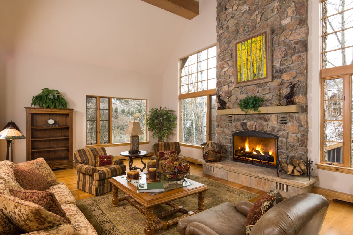 Huge rustic inspired barnhouse matched with wooden flooring, beige walls and brown leather sofas with a huge fireplace decorated with stones