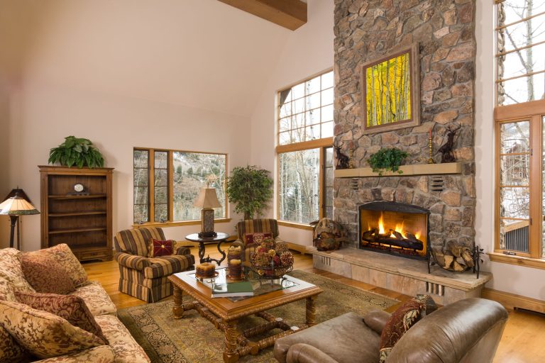 Huge rustic inspired barnhouse matched with wooden flooring, beige walls and brown leather sofas with a huge fireplace decorated with stones, Chocolate Brown Sofa - What Color Walls?