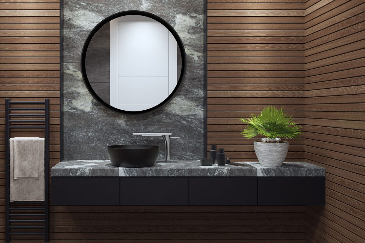 Interior of a gorgeous bathroom with wooden paneling walls, a black cabinet with plants and matched with a huge round mirror