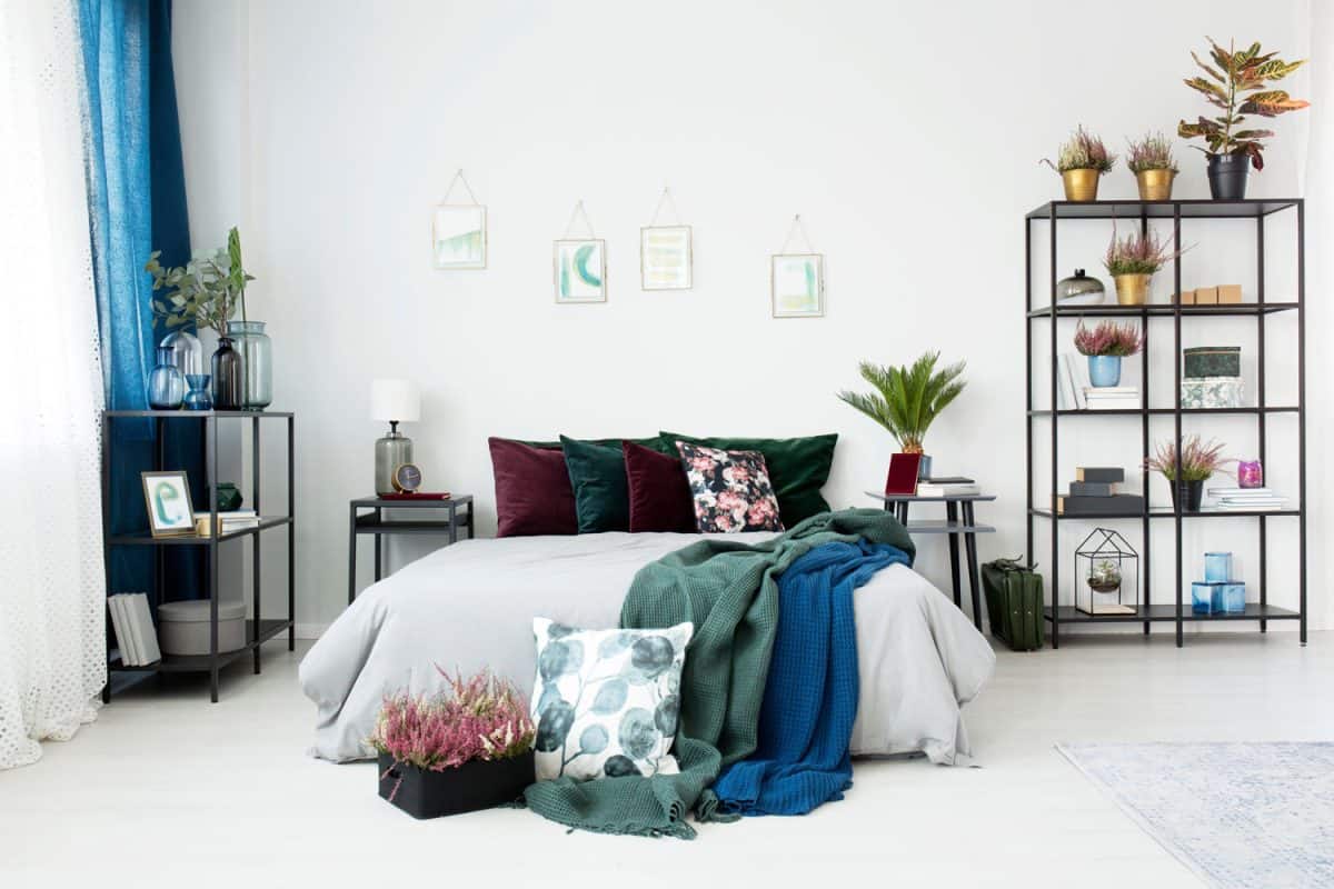 Interior of a white and industrial themed bedroom with colored pillows and flowers for diversity