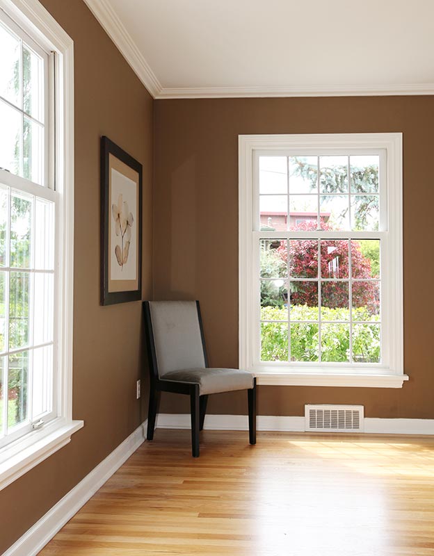 Living room corner with chair and two windows and hardwood floor