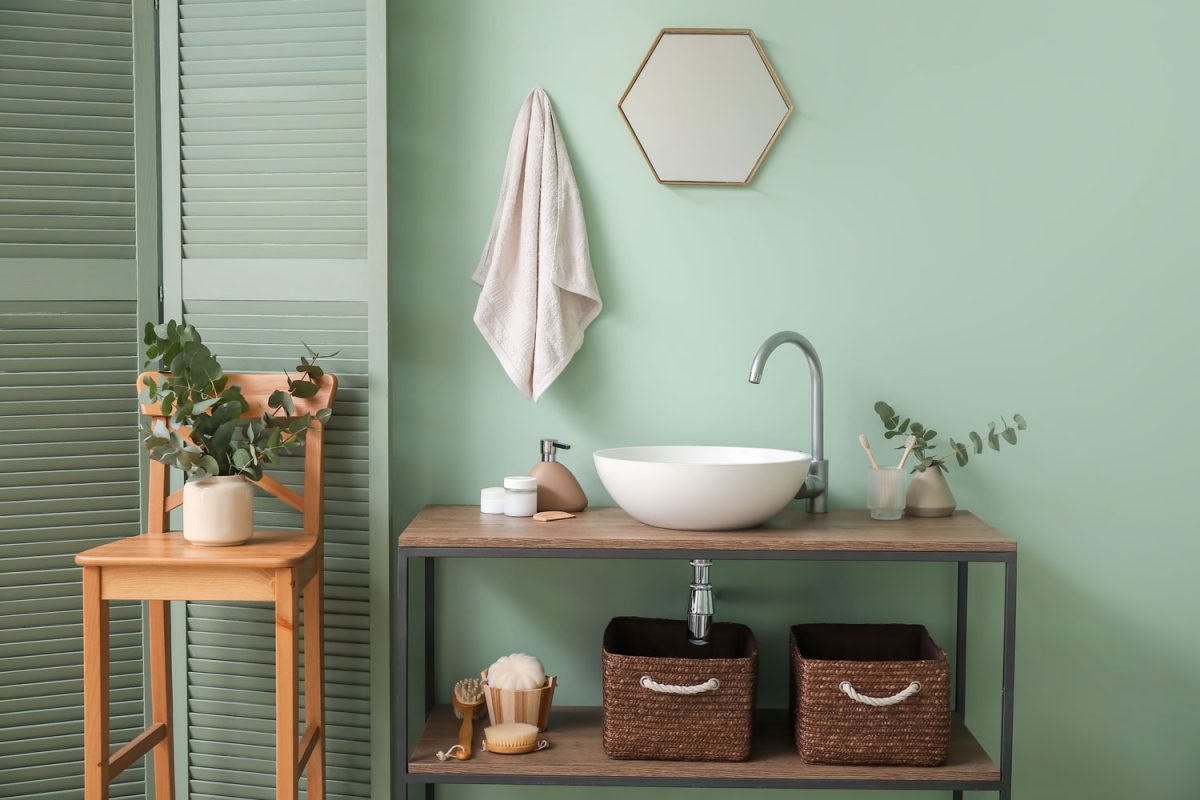 Minimalist inspired bathroom painted in green and decorated with indoor plants and wooden furnitures