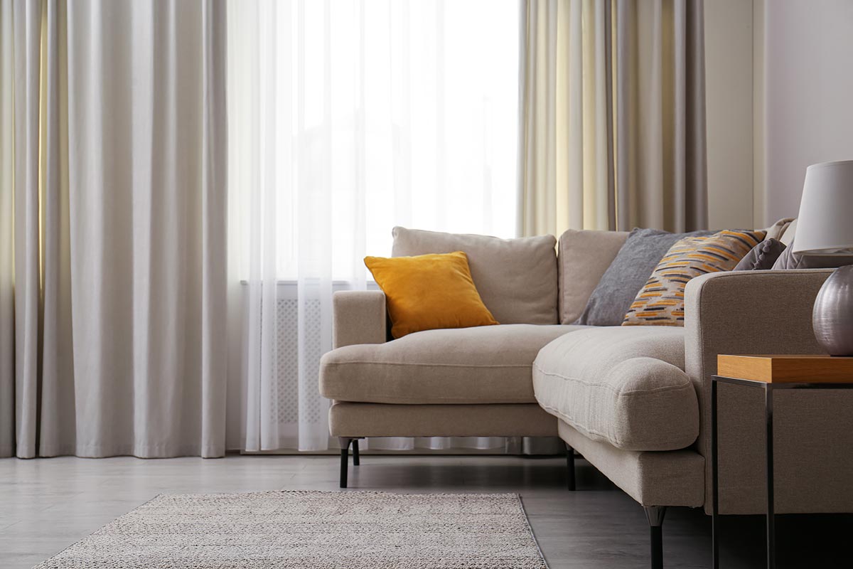 Modern comfortable sofa near window in stylish living room
