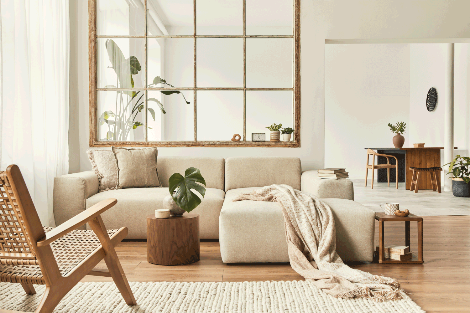 Modern interior of open space with design modular sofa, furniture, wooden coffee tables, plaid, pillows, tropical plants. cream color concept