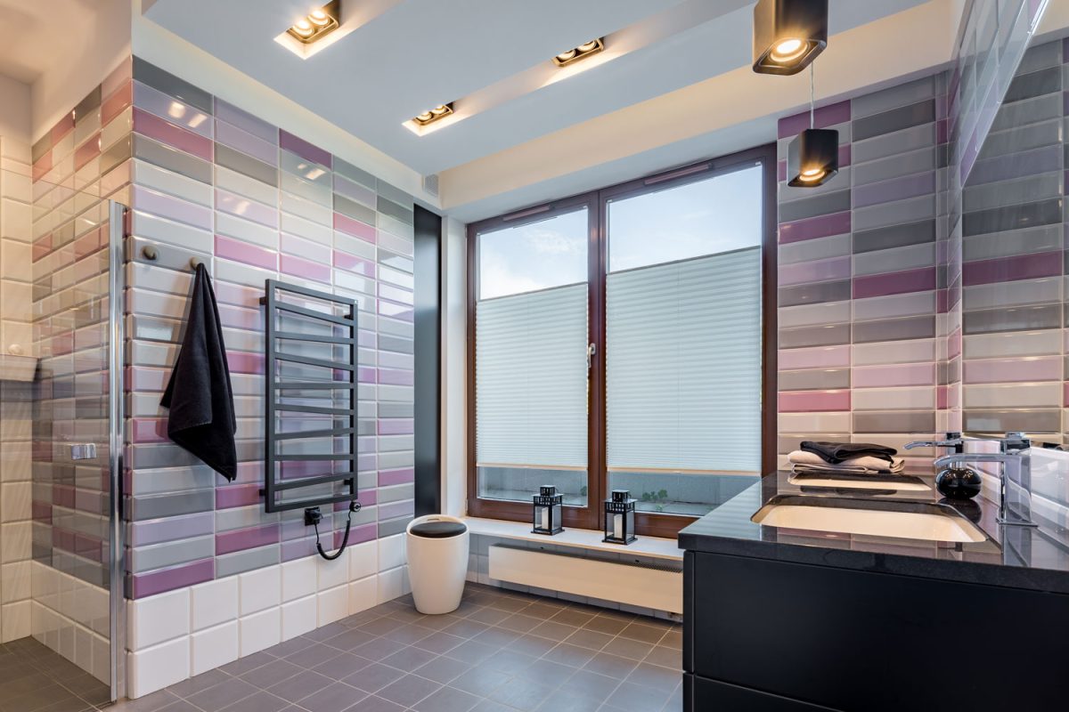 Multi colored bathroom cladding, cabinet painted in black and huge spotlight type lighting