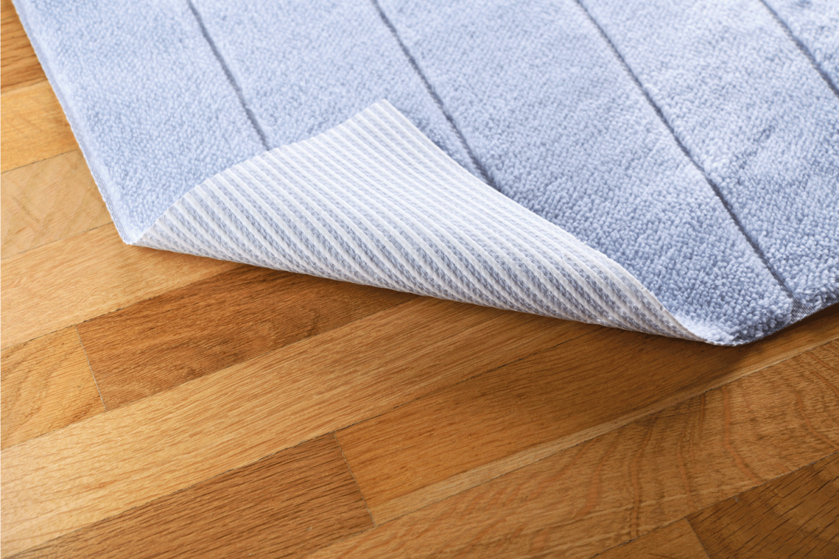 On the parquet floor is a bright blue foot mat with a rolled edge.