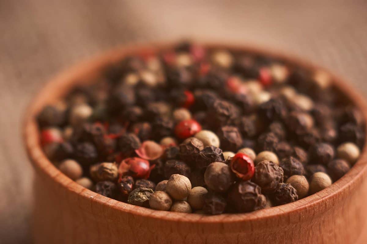 Peppercorns in a wooden bowl on table with food rustic style