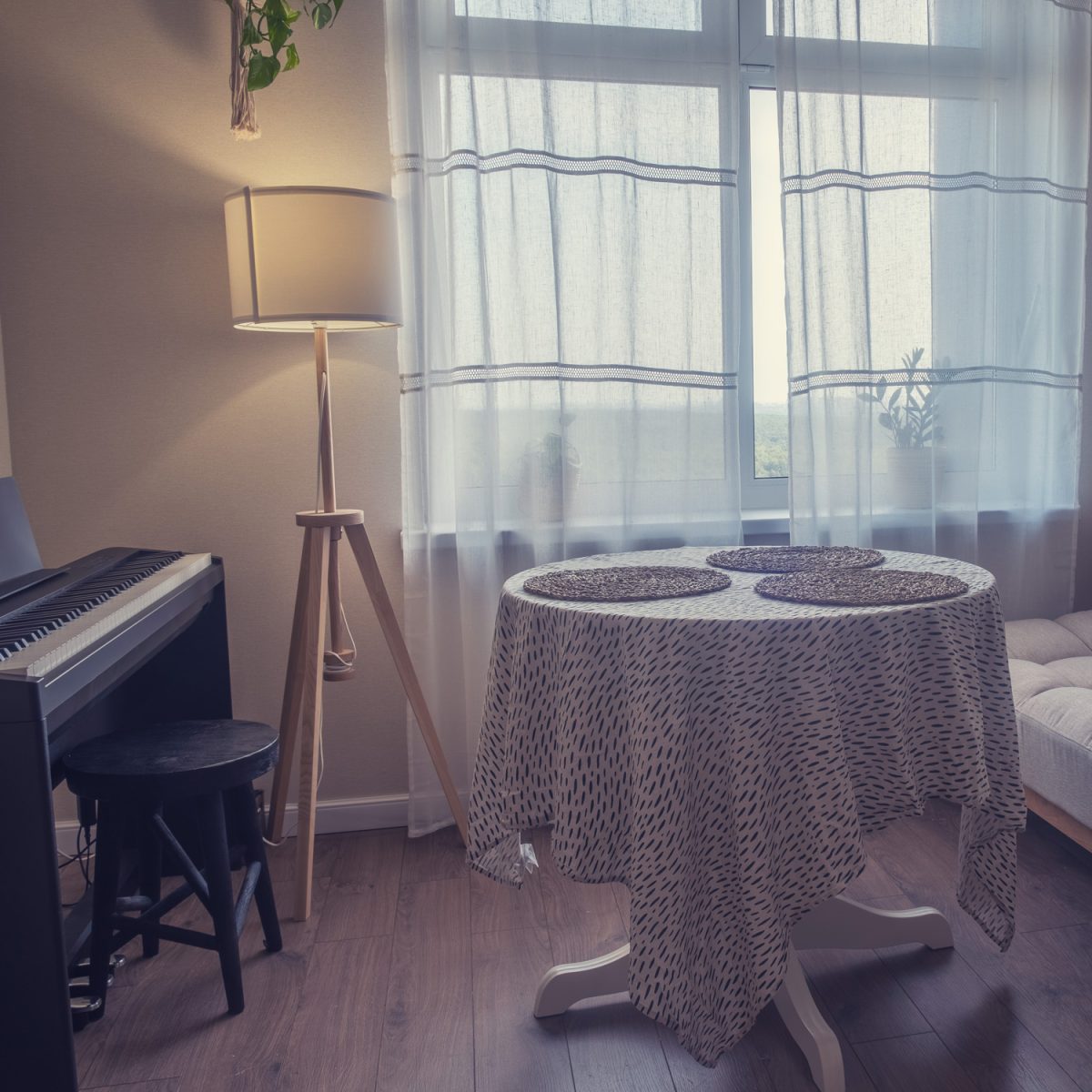 Room interior with table, couch and synthesizer. Window with a floor lamp in a living room with a musical instrument

