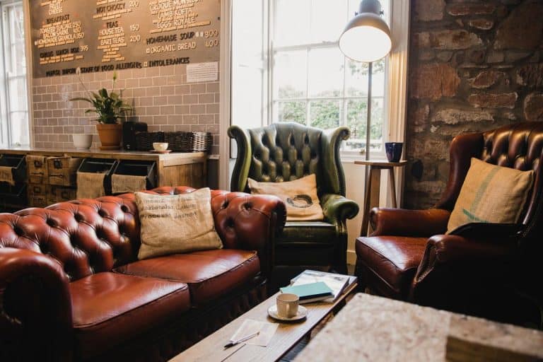 A seating area in a small cafe with leather sofas and a wooden table, What Accent Chairs Go With A Leather Sofa?