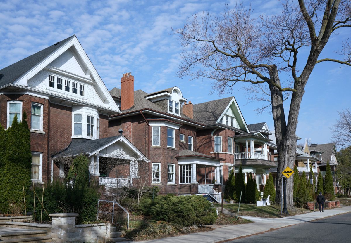 Street with row of large older brick detached houses with gables

