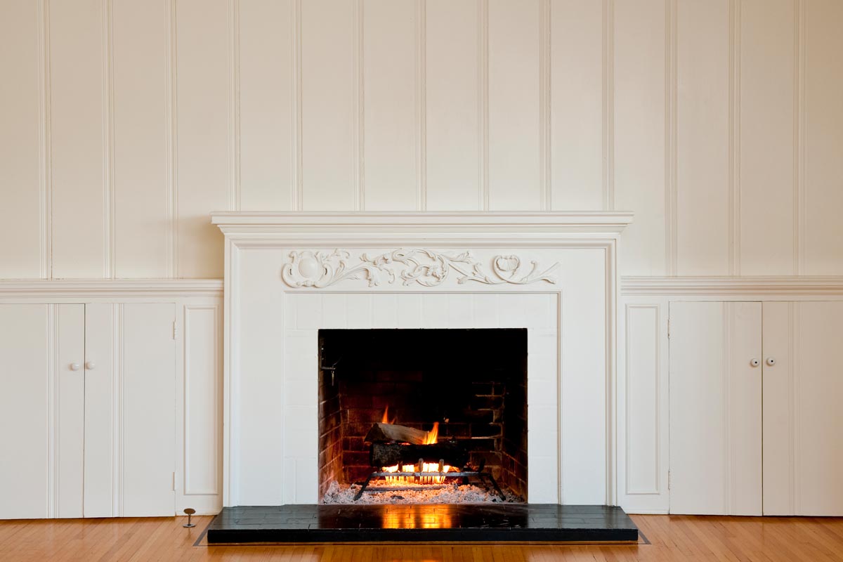 A traditional fireplace with floral relief moulding in empty domestic room, What Color To Paint Fireplace Surround
