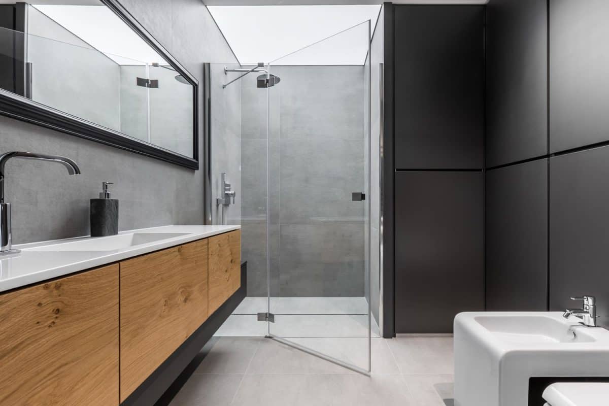 Ultra luxurious modern bathroom with gray and black tile walls with a wooden vanity