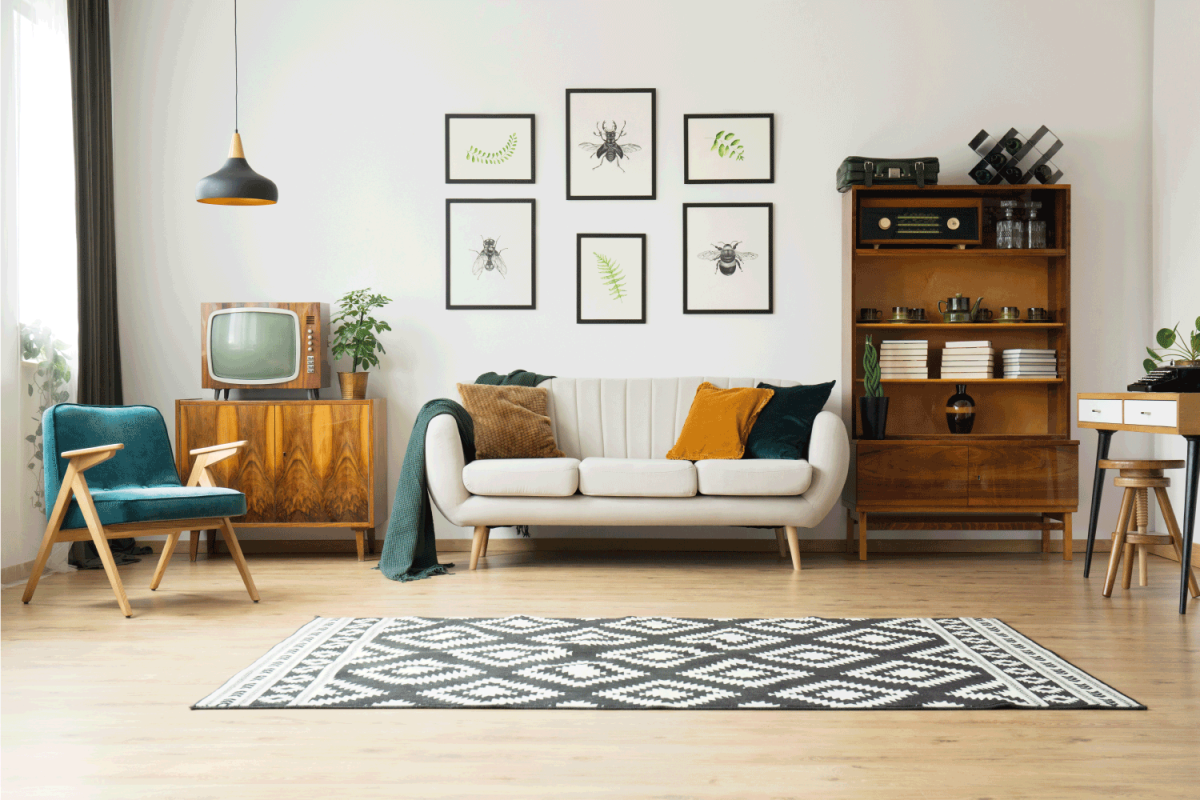 Vintage tv standing on a wooden cabinet next to a comfy couch in a stylish day room interior. white concept