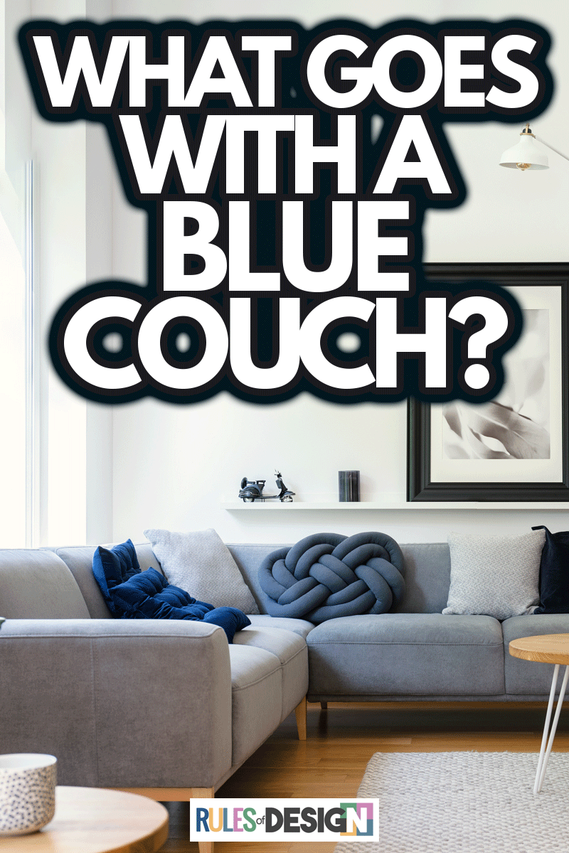 Poster on white wall in living room interior with table in front of corner sofa with pillows, What Goes With A Blue Couch?