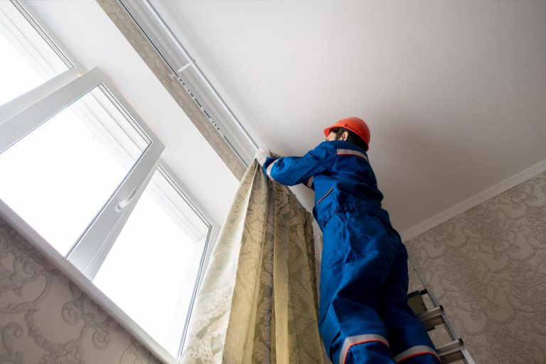A worker repairman hanging and fixing the curtain on the window, How To Hang Curtains With 10 Foot Ceilings