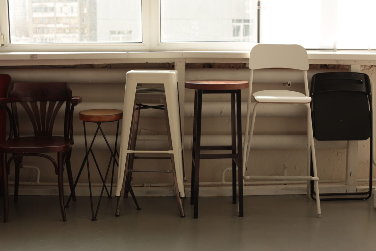various different set of chairs stools stand along the wall by the window
